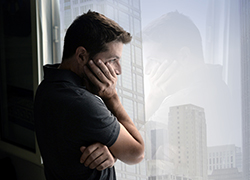 man looking out the window depressed