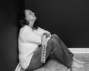 woman sitting on floor holding pillbox looking upset