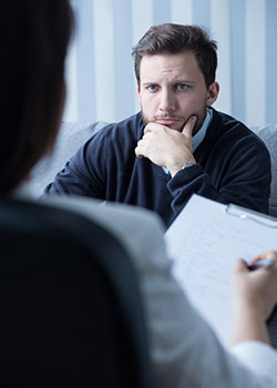 Man seated with chin in hand