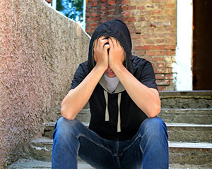 Young man sitting on steps with head in hands