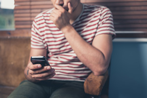 Young man holding phone wondering what questions to ask depression hotline